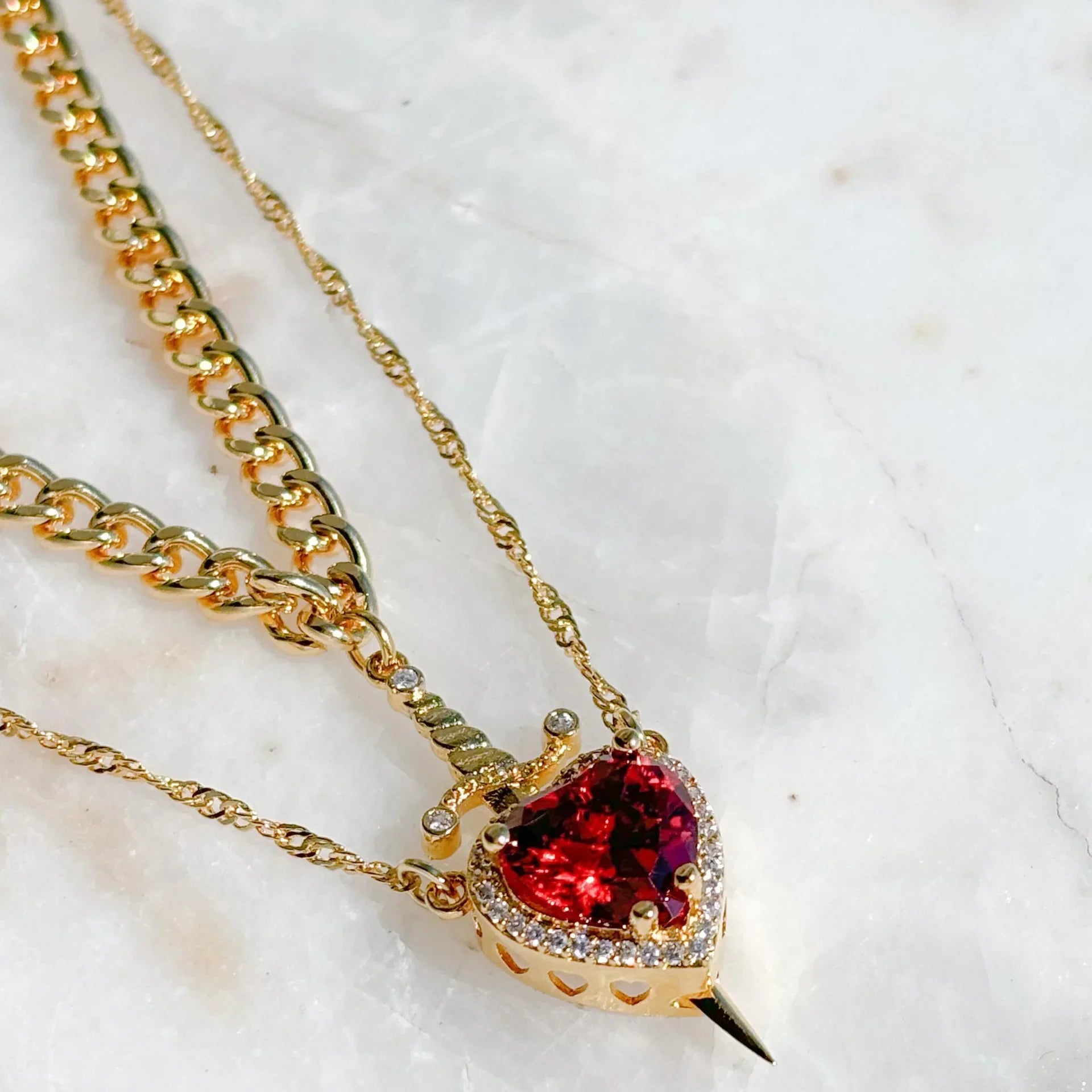 Golden Ruby Themed Pendant Jewelry with a sword and heart placed on a white background