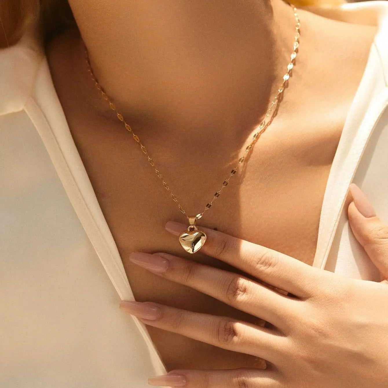 A woman wears the gold heart necklace